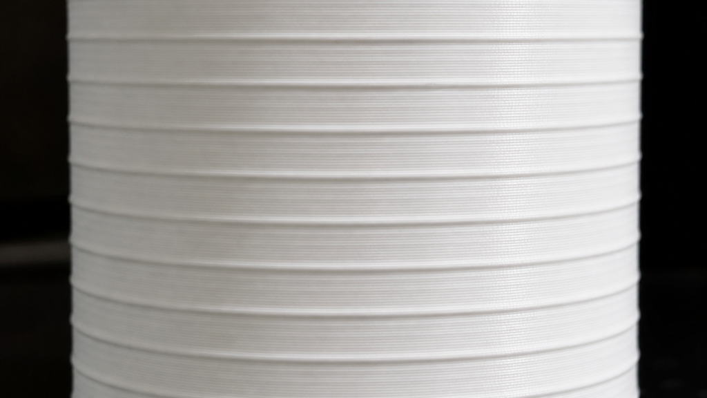 White printed cylinder with regularly repeating horizontal bands around its wall.